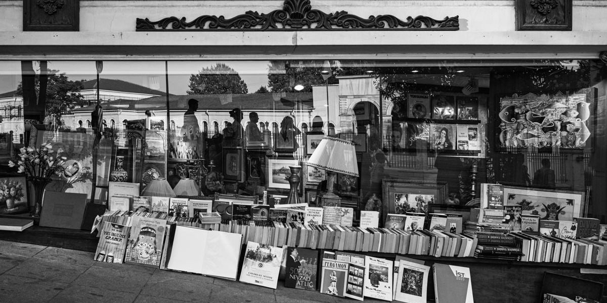 Monochrome view of books and reflections in a decorative storefront window.